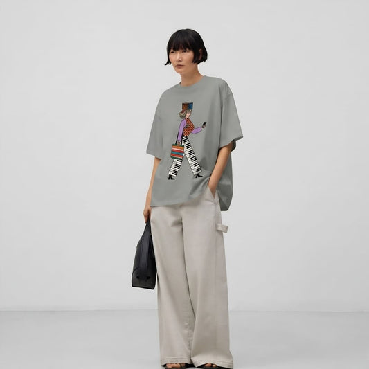 Person wearing a gray t-shirt with a colorful graphic and beige pants on a white background