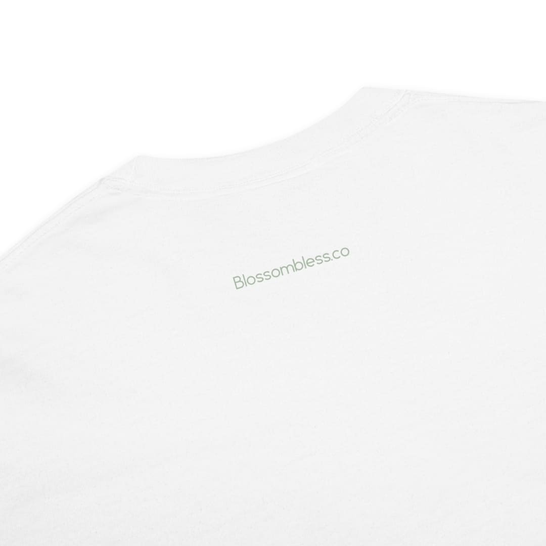 Close-up of a white crewneck t-shirt with the brand name 'Blossomblessco' printed in a light sage green font on the upper chest.