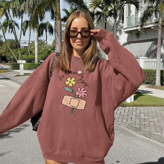 Woman wearing a red sweatshirt with a graphic design outdoors.