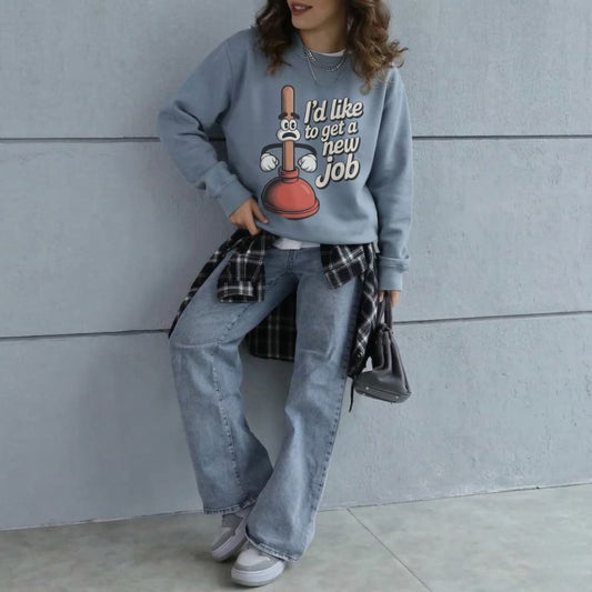 Person wearing a blue sweatshirt with a humorous design, standing against a plain wall.