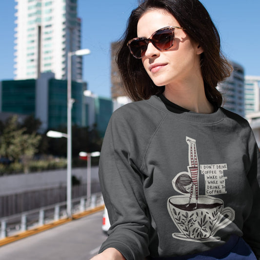 Woman wearing a dark gray sweatshirt with a coffee-themed graphic in an urban setting.