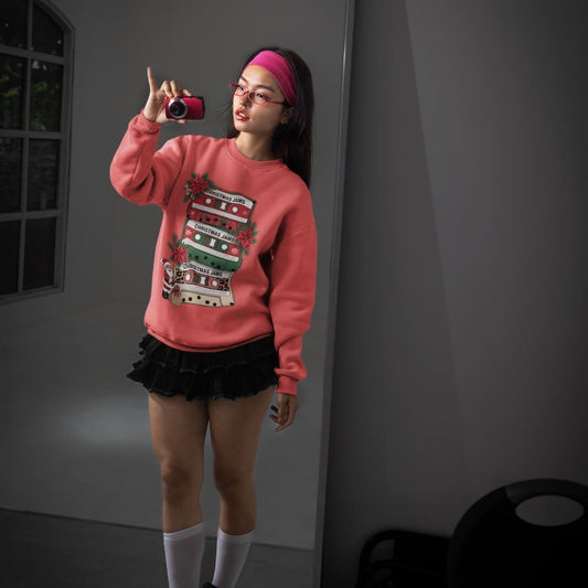 Person wearing a pink sweatshirt with a graphic design, taking a selfie in a room.