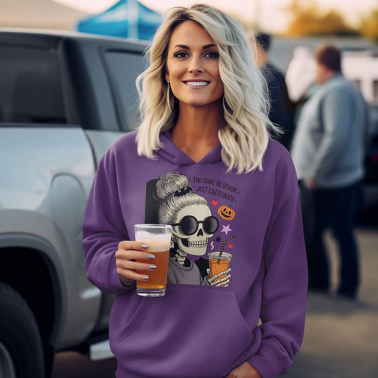 Woman wearing a purple hoodie with a graphic design, holding a drink in an outdoor setting.