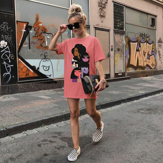 Woman wearing a pink t-shirt with graphic design, sunglasses, and checkered shoes on a street with graffiti.
