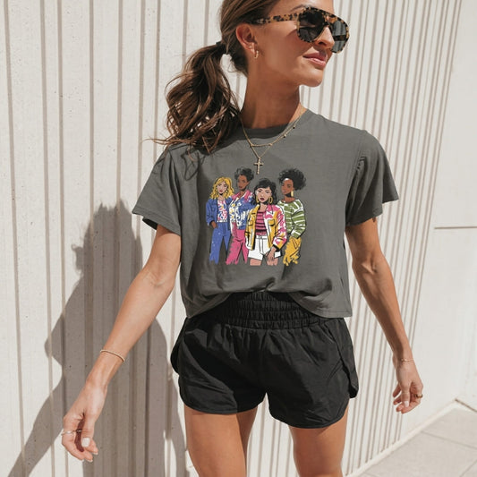 Woman wearing a graphic gray t-shirt with colorful illustrations against a light-colored wall.