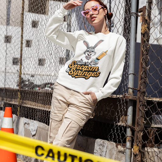 Person wearing a white sweatshirt with a graphic design, standing near a chain-link fence and caution tape.