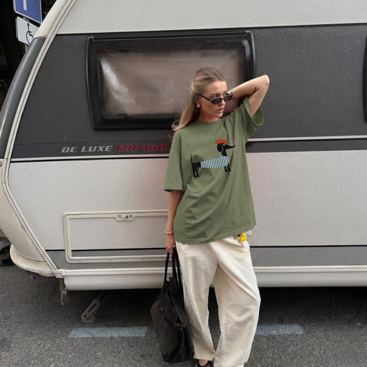 Woman wearing a green t-shirt with a graphic design, standing in front of a vintage camper van.