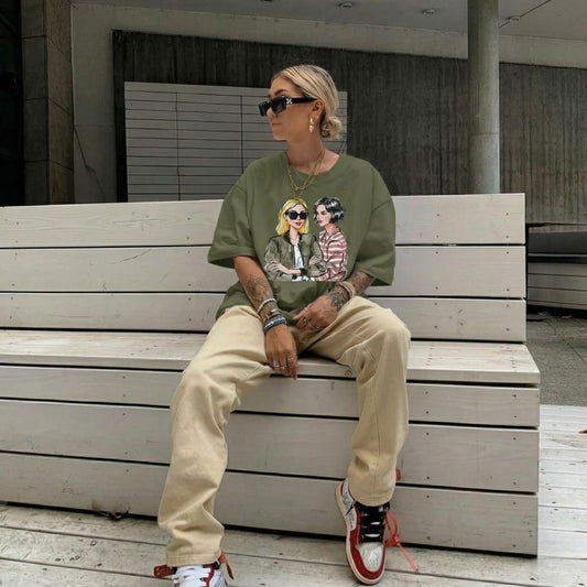 Person sitting on a bench wearing a green graphic t-shirt and beige pants.