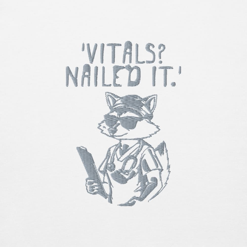 Raccoon nurse graphic wearing scrubs and sunglasses holding a clipboard under the quote “Vitals? Nailed It.” – printed on a black Cotton Heritage hoodie