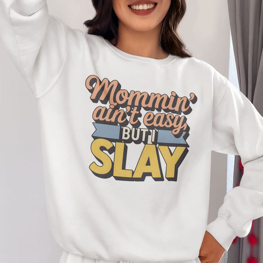 “Mommin' Ain’t Easy But I Slay” retro-style DTG printed design in peach, blue, and yellow on vintage garment-dyed fleece sweatshirt