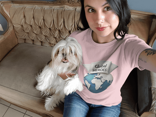 Person wearing a pink 'Global Heroes' t-shirt sitting with a white dog on a brown couch.