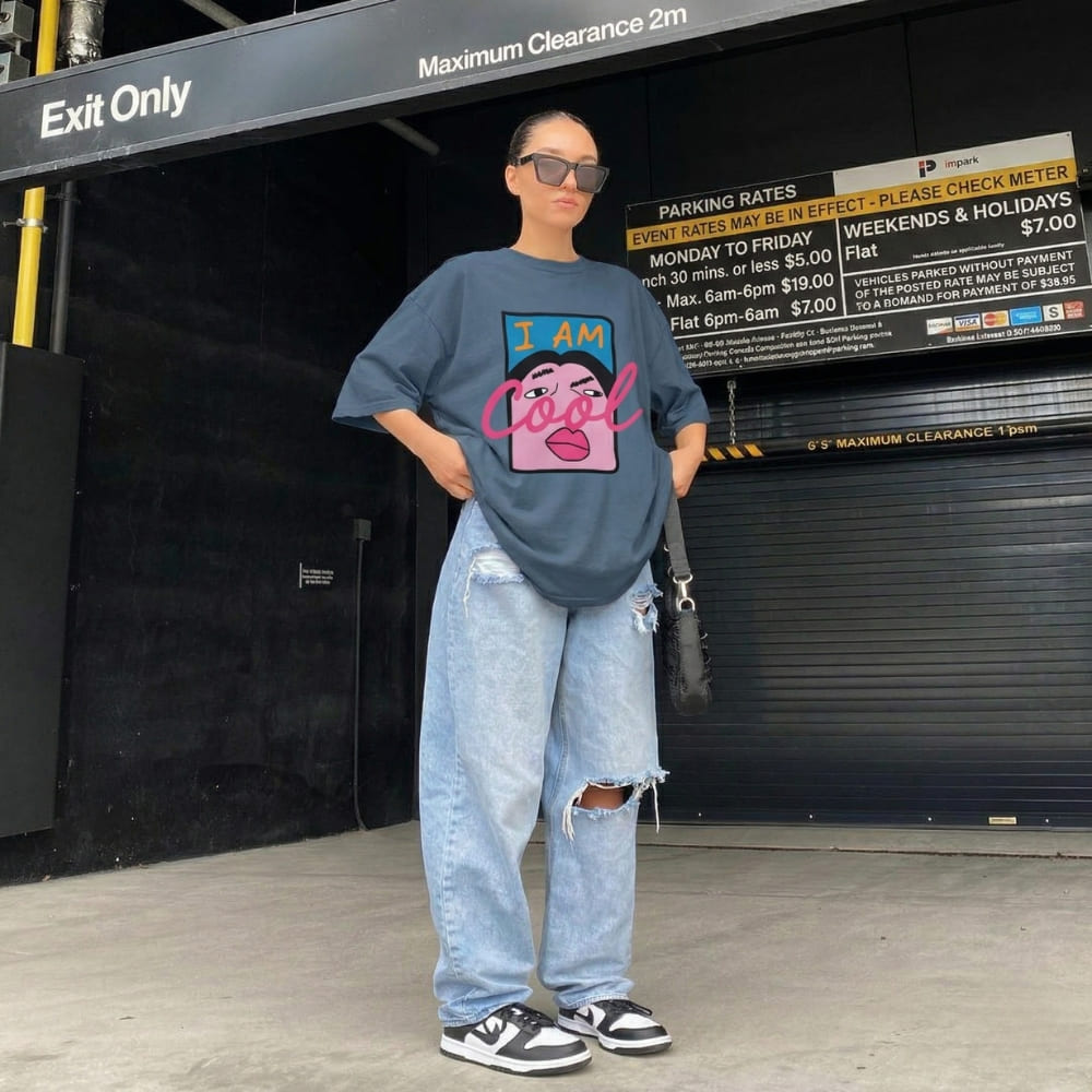 Person wearing a graphic t-shirt and jeans standing in front of a garage door with parking rates displayed.