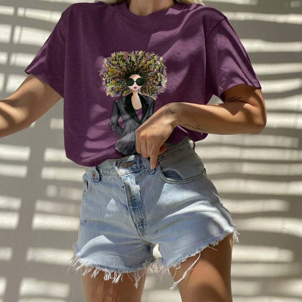 Person wearing a purple t-shirt with a graphic design and denim shorts against a light background