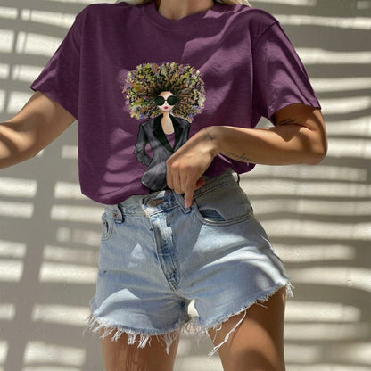 Person wearing a purple t-shirt with a graphic design and denim shorts against a light background