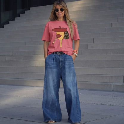 Woman wearing a pink t-shirt with a graphic design and blue jeans standing on steps.