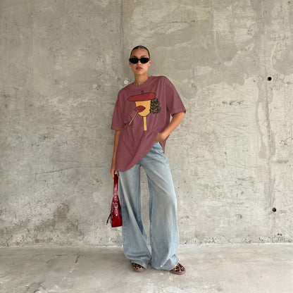 Person wearing a graphic t-shirt and light blue jeans against a concrete wall.