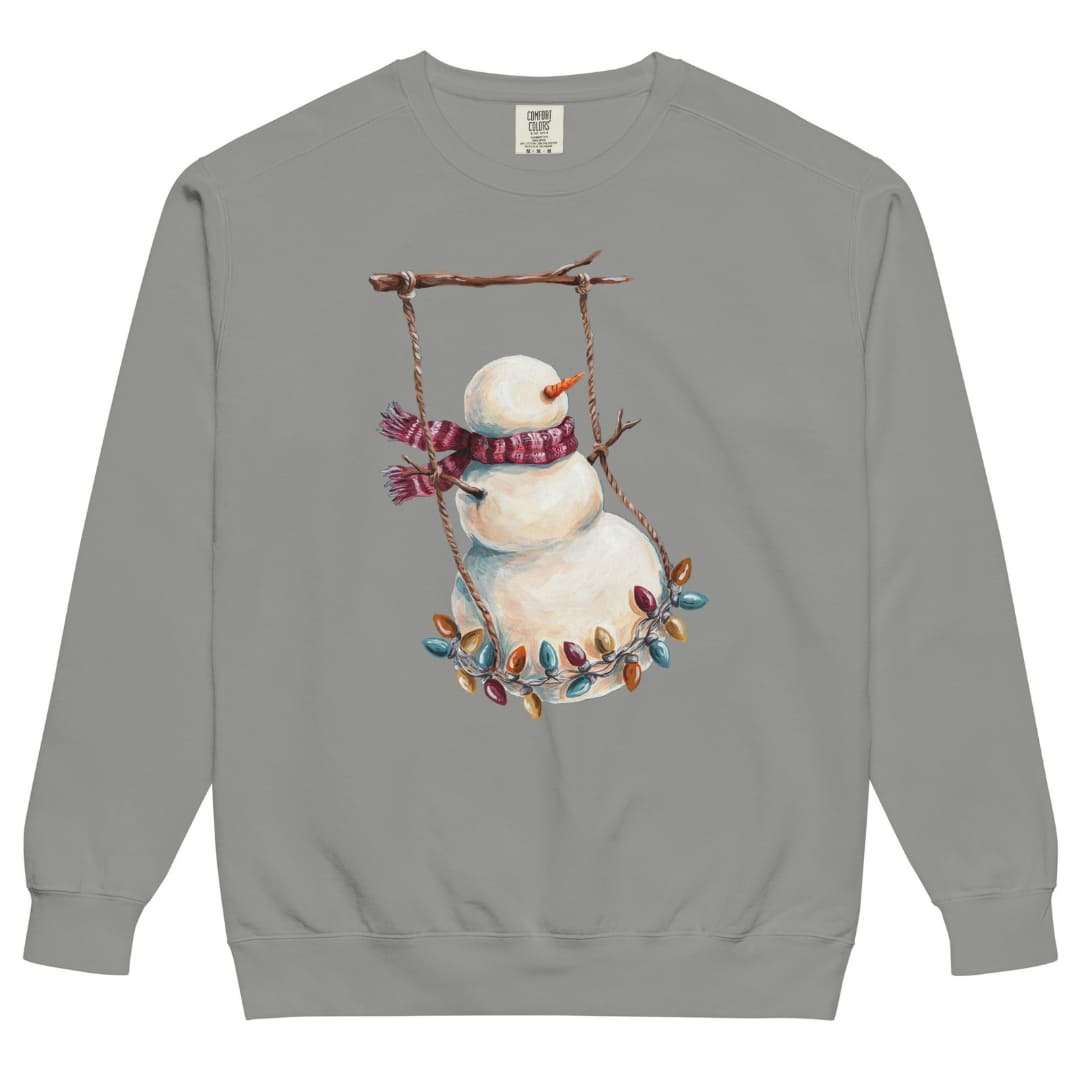 Swing Season™ sweatshirt by Blossombless.co in Grey, front view: a painterly snowman swinging on a strand of vintage Christmas lights from a bare winter branch, wearing a striped burgundy scarf