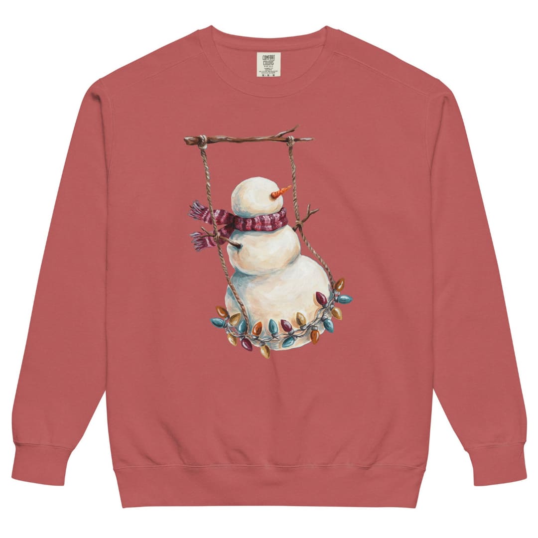 Swing Season™ sweatshirt by Blossombless.co in Crimson, front view: a painterly snowman swinging on a strand of vintage Christmas lights from a bare winter branch, wearing a striped burgundy scarf