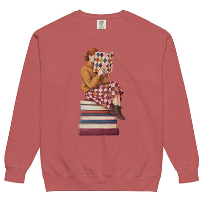 Between Chapters™ sweatshirt by Blossombless.co in Crimson, front view: a painterly woman perched on a stack of books, her face hidden behind a harlequin hardcover