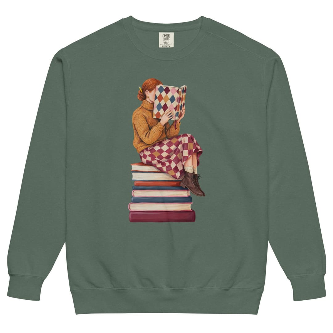 Between Chapters™ sweatshirt by Blossombless.co in Blue Spruce, front view: a painterly woman perched on a stack of books, her face hidden behind a harlequin hardcover