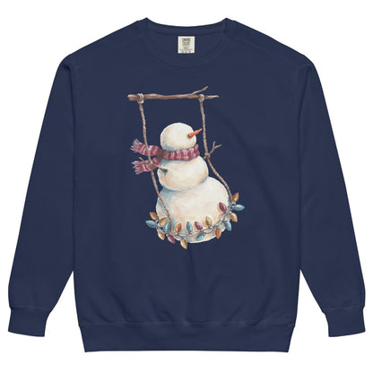 Swing Season™ sweatshirt by Blossombless.co in True Navy, front view: a painterly snowman swinging on a strand of vintage Christmas lights from a bare winter branch, wearing a striped burgundy scarf