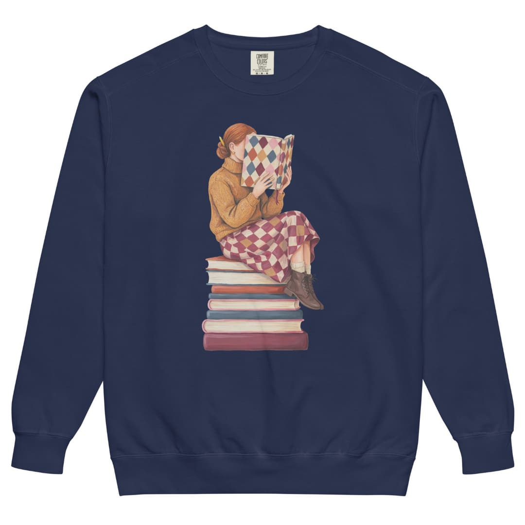 Between Chapters™ sweatshirt by Blossombless.co in True Navy, front view: a painterly woman perched on a stack of books, her face hidden behind a harlequin hardcover