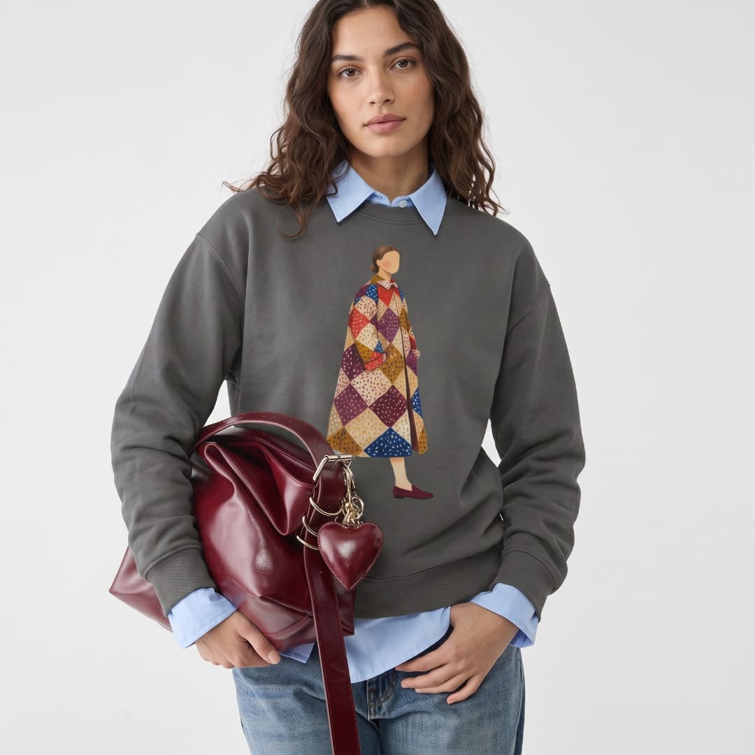 Woman wearing the Pieced Together™ sweatshirt by Blossombless.co in Pepper over a light blue collared shirt, holding a burgundy leather bag