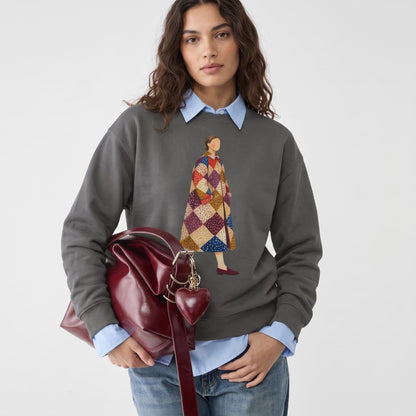 Woman wearing the Pieced Together™ sweatshirt by Blossombless.co in Pepper over a light blue collared shirt, holding a burgundy leather bag