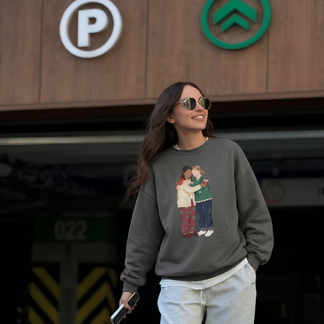 Woman wearing the Charted With Love™ sweatshirt by Blossombless.co in Pepper with light jeans and sunglasses, standing outside a parking garage