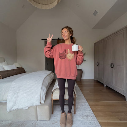 Woman wearing the Belle & Plume™ sweatshirt by Blossombless.co in Crimson with black leggings, holding a mug in a calm bedroom