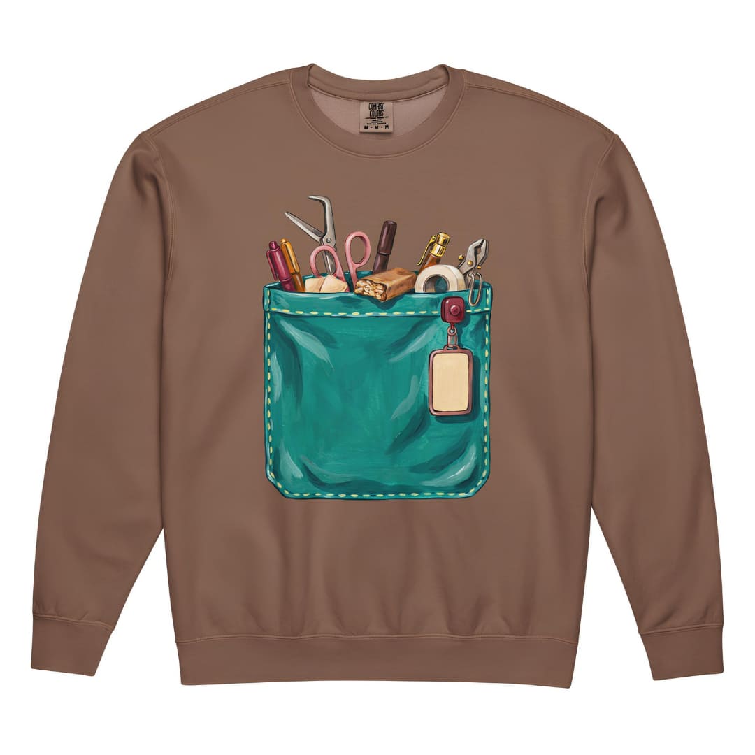 The Shift Pocket™ nurse sweatshirt in Espresso, front view: hand-painted teal scrub pocket holding trauma shears, a hemostat, pens, tape and a badge reel