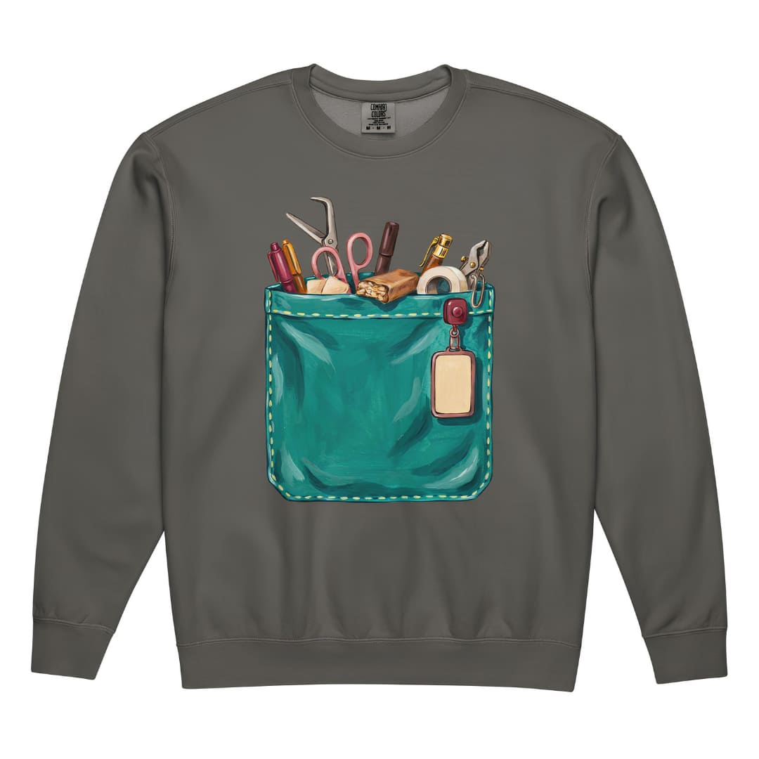 The Shift Pocket™ nurse sweatshirt in Pepper, front view: hand-painted teal scrub pocket holding trauma shears, a hemostat, pens, tape and a badge reel