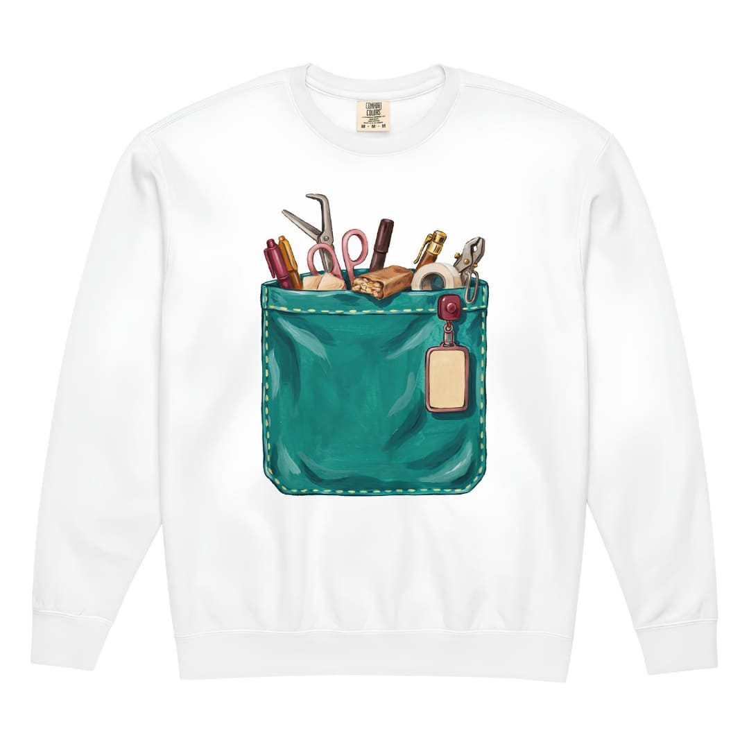 The Shift Pocket™ nurse sweatshirt in White, front view: hand-painted teal scrub pocket holding trauma shears, a hemostat, pens, tape and a badge reel