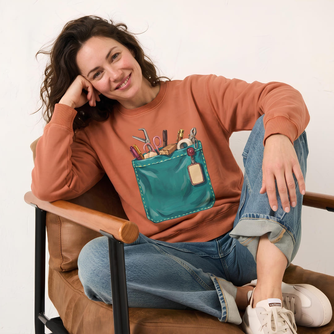 Woman wearing The Shift Pocket™ sweatshirt in Yam, relaxing in a leather armchair with light-wash jeans