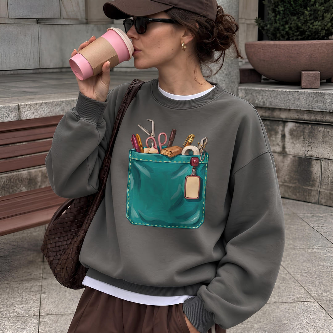 Woman wearing The Shift Pocket™ sweatshirt in Pepper on a city sidewalk, sipping from a pink cup