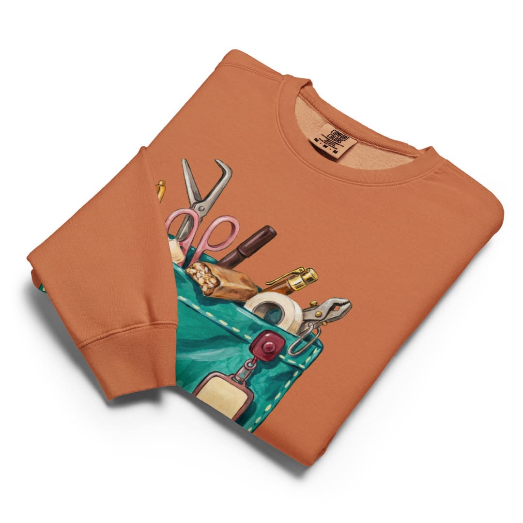 The Shift Pocket™ sweatshirt in Yam, folded flat with the hand-painted scrub pocket design on the chest