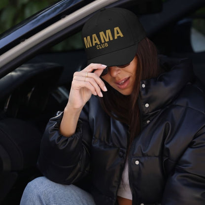 Person wearing a black cap with 'MAMA CLUB' text, sitting inside a vehicle.