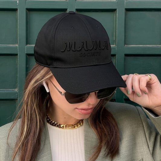 Person wearing a black cap with 'MAMA SOCIETY' text against a green background