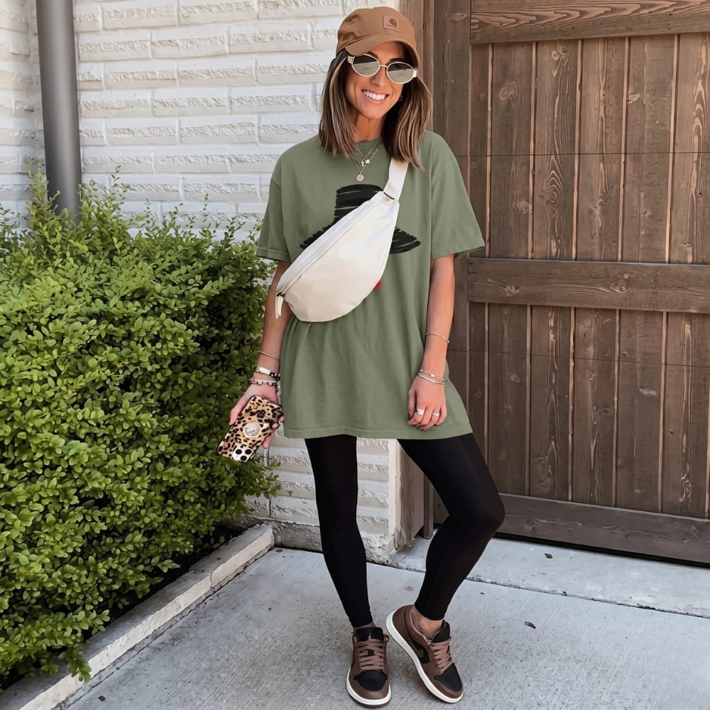 Woman wearing a green t-shirt dress, black leggings, and brown sneakers, standing outdoors.
