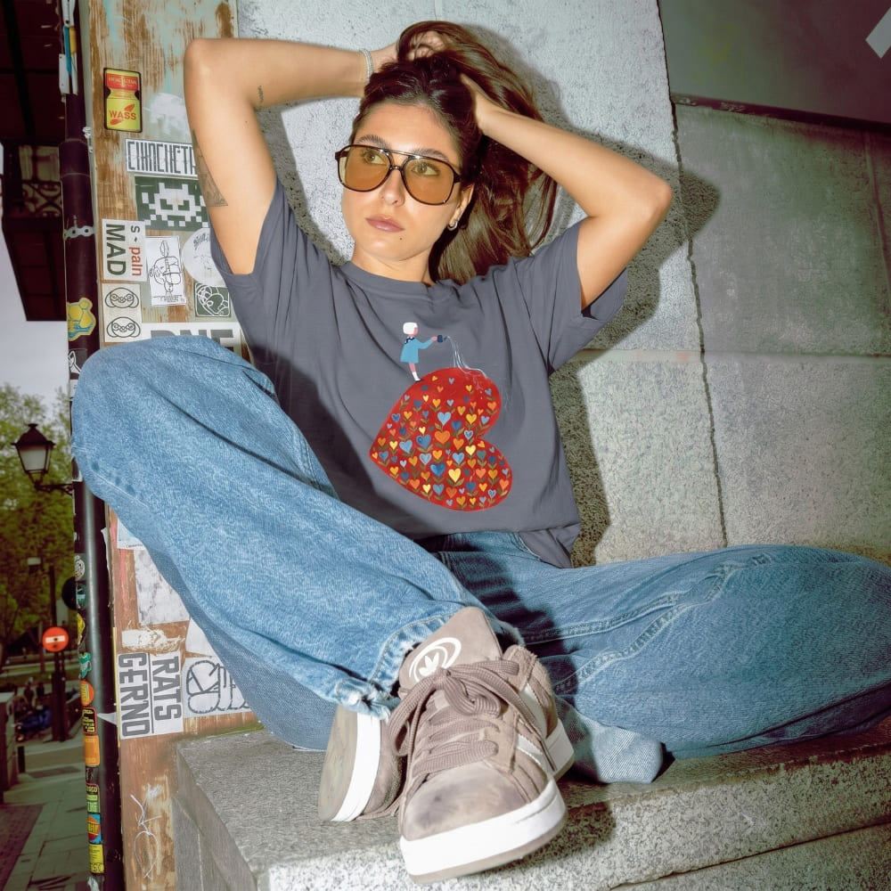 Person sitting on a step wearing a graphic t-shirt and jeans in an urban setting