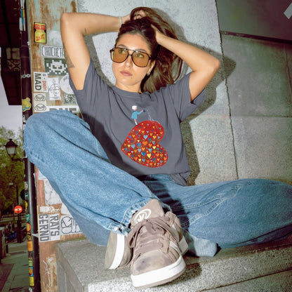 Person sitting on a step wearing a graphic t-shirt and jeans in an urban setting