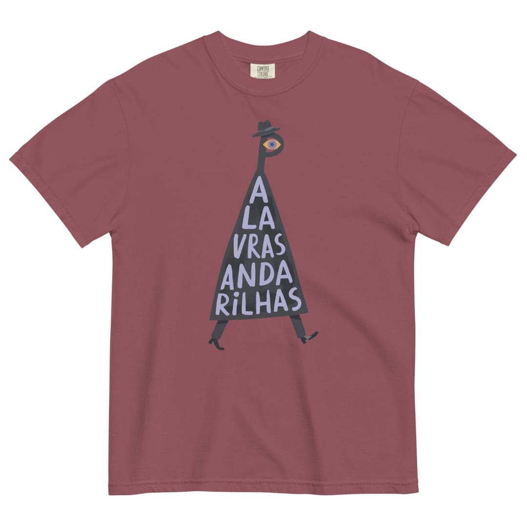 A dusty rose short-sleeve crewneck t-shirt featuring a graphic of a walking figure made of the letters 'A L A V R A S A N D A R I L H A S' in white on a black triangle, with a small eye at the top and a black hat. The shirt is displayed flat against a solid white background.