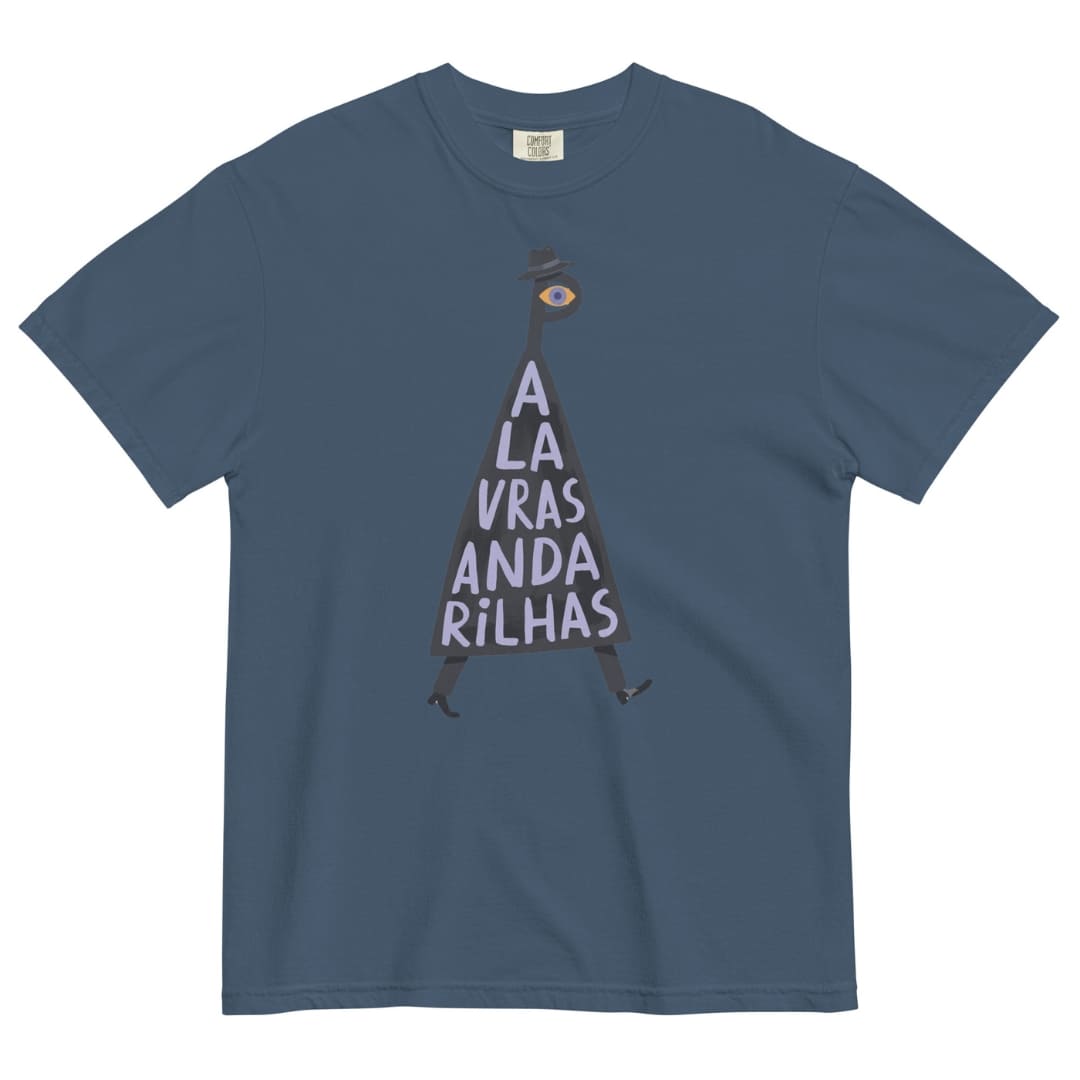 A slate blue crewneck t-shirt featuring a graphic of a dark silhouette shaped like the letter 'A', with a single eye on its head and the Portuguese text 'A LA VRAS ANDA RILHAS' printed in white inside the silhouette.
