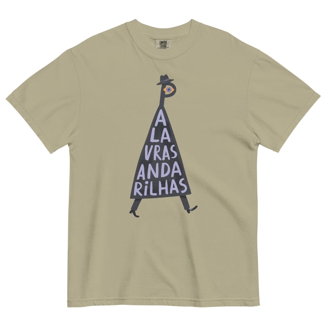 A beige short-sleeve crewneck t-shirt featuring a graphic illustration of a walking figure in a black hat and coat with the text 'A LA VRAS ANDA RILHAS' printed on the front.