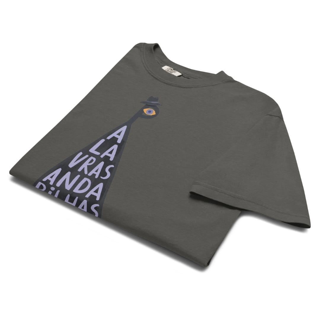 A dark gray t-shirt with a graphic print of a spotlight shining on the text 'A LA VRAS ANDA PELLIAS' in light purple, shown on a clean white background.