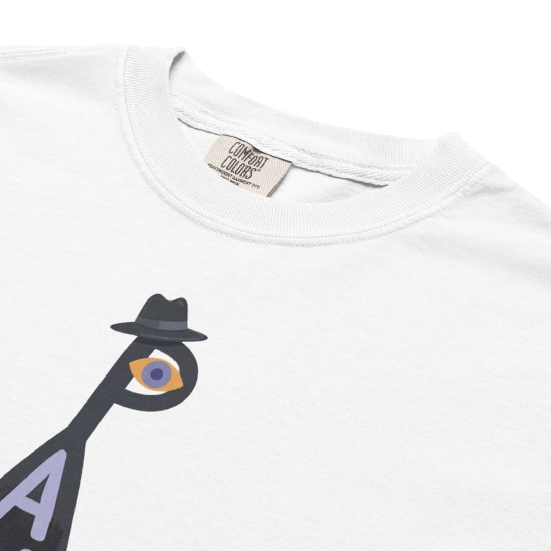 Close-up of a white crewneck t-shirt featuring a graphic of a black silhouette figure wearing a fedora and an eye with a purple iris, with a visible Comfort Colors neck label.