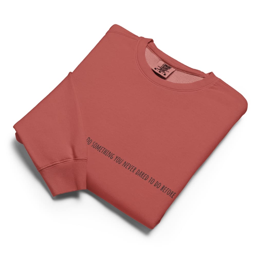 Folded terracotta-colored sweatshirt with a motivational quote on a white background
