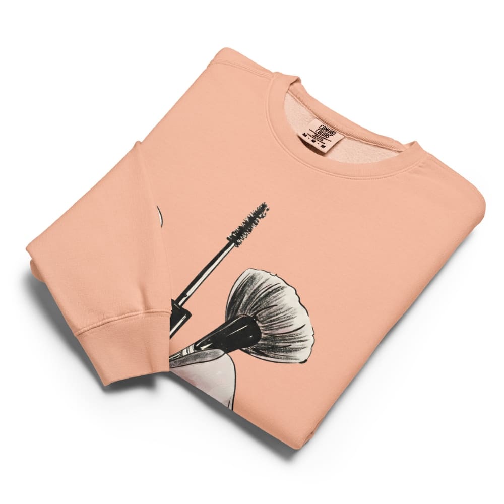 Folded peach-colored sweatshirt with a graphic design on a white background
