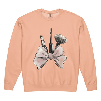 Peach sweatshirt with makeup graphic and bow design on a white background
