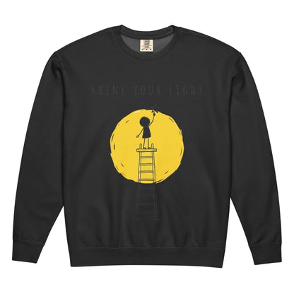 Black sweatshirt with a yellow graphic of a person on a ladder reaching for the text 'Shine Your Light' on a white background.